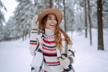 Kürk manto, eşarp ve kış ormanında poz veren güzel bir kadın. Açık havada poz veren mutlu bayan turist. Noel.