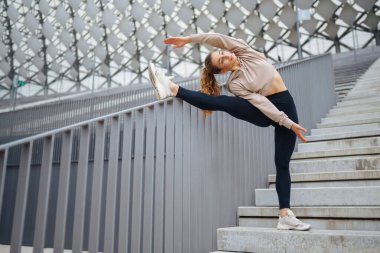 Havalı spor kıyafetleriyle spor yapan kadın dışarıda spor yapıyor. Genç bir kadın egzersiz yapıyor, esneme egzersizleri yapıyor. Aktif yaşam tarzı konsepti, spor.