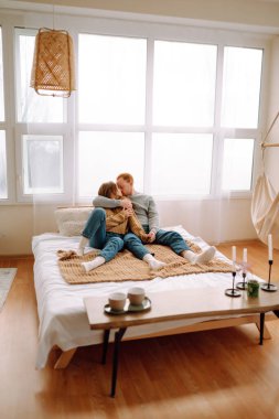 Young couple resting in bed at home. A couple in love spends time together on the bed, hugs each other, gives gifts and has fun. Holiday concept.