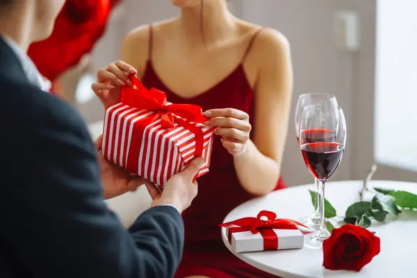 Young couple in love celebrates Valentine\'s Day. A man and a woman are enjoying time together in a restaurant, giving gifts, relaxing. Concept of romance, love.