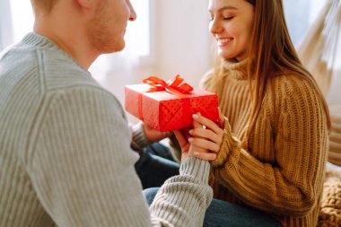 Birbirine aşık çiftler yatakta birlikte vakit geçiriyorlar. Erkek ve kadın evde rahatlar ve yatakta eğlenirler. Tatil, aşk, hediye kavramı.