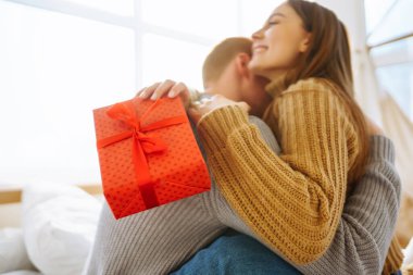 Birbirine aşık çiftler yatakta birlikte vakit geçiriyorlar. Erkek ve kadın evde rahatlar ve yatakta eğlenirler. Tatil, aşk, hediye kavramı.