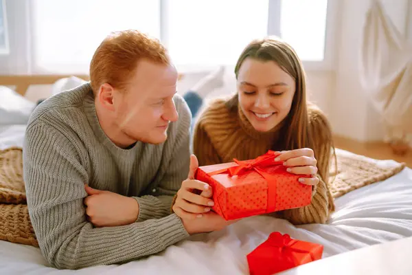 年轻漂亮的一对恋人在家里 用礼品盒交换庆祝 情人节的概念 浪漫的一天 — 图库照片