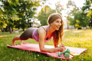 Parkta egzersiz yaparken yoga yapan genç bir kadın. Fitness. Etkin yaşam biçimi.