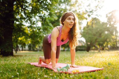 Parkta egzersiz yaparken yoga yapan genç bir kadın. Fitness. Etkin yaşam biçimi.
