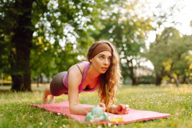 Parkta egzersiz yaparken yoga yapan genç bir kadın. Fitness. Etkin yaşam biçimi.