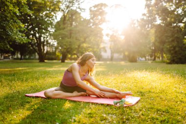 Parkta egzersiz yaparken yoga yapan genç bir kadın. Fitness. Etkin yaşam biçimi.