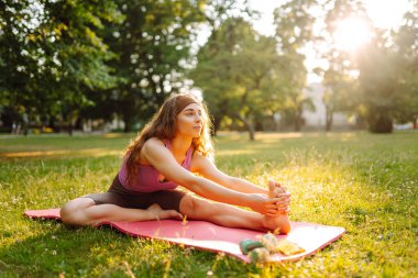Parkta egzersiz yaparken yoga yapan genç bir kadın. Fitness. Etkin yaşam biçimi.