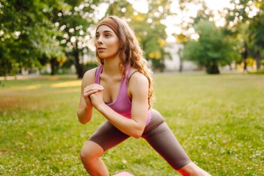Parkta egzersiz yaparken yoga yapan genç bir kadın. Fitness. Etkin yaşam biçimi.