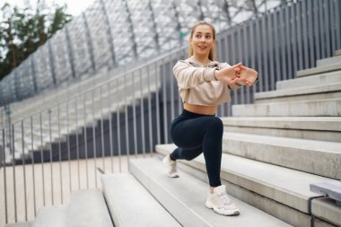 Spor kıyafetli mutlu kadın sabahları dışarıda egzersiz yapıyor. Spor kadını esneme egzersizi yapıyor. Spor, aktif yaşam, spor eğitimi, sağlıklı yaşam tarzı..