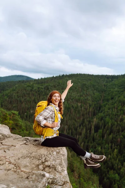 Young woman  with backpack on mountain peak looking in beautiful mountain. Landscape with sporty young woman, green hills. Hiking. Nature. Travel and tourism.