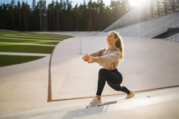 Happy woman in sports outfit doing exercises outdoors in the morning. Sport woman doing stretching exercise. Sport, Active life, sports training, healthy lifestyle.