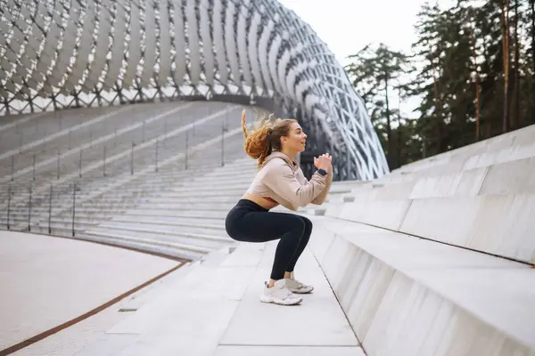 Happy woman in sports outfit doing exercises outdoors in the morning. Sport woman doing stretching exercise. Sport, Active life, sports training, healthy lifestyle.