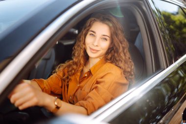 Mutlu bir kadın araba sürüyor ve gülümsüyor. Otomobil yolculuğu. Aynı arabayı paylaşıyoruz. Yaşam tarzı kavramı.