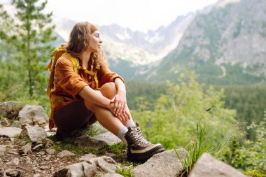 Yürüyüş parkurunda, açık bir dağın tepesinde, yürüyüş botlarıyla kadın bacaklarının yakın çekimi. Seyahat, tatil. Doğa konsepti, rahatlama, yürüme.