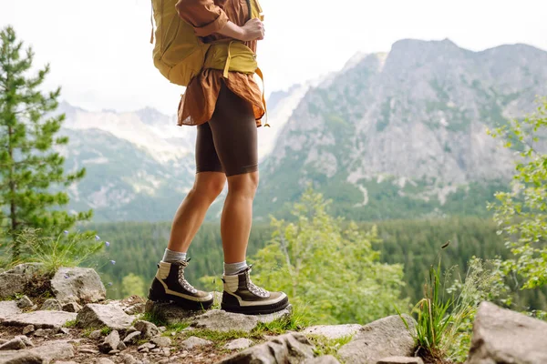 Close-up of female legs in hiking boots on a hiking trail, on top of a mountain outdoors. Travel, vacation.  The concept of nature, relaxation, walking.