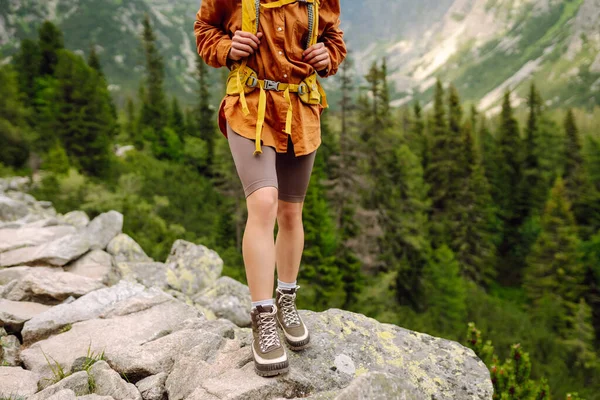 Close-up of female legs in hiking boots on a hiking trail, on top of a mountain outdoors. Travel, vacation.  The concept of nature, relaxation, walking.