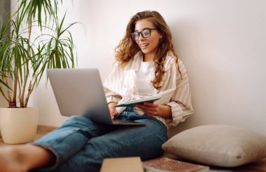 Genç kadın evde oturuyor, edebiyat ve laptop, bilgi ve eğitim kavramını kullanarak sınava hazırlanıyor..