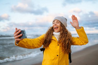 Genç bir kadın selfie çekiyor ve deniz manzarasının tadını çıkarıyor. Seyahat, yaşam tarzı, macera. Selfie zamanı. Günlük tutma.  