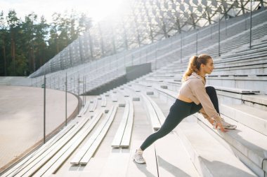 Sokakta spor yapan bir kadın. Fitness ve sağlıklı bir yaşam tarzı. Antrenör vücudu germek için egzersiz yapar. Spor, aktif yaşam, spor eğitimi, sağlıklı yaşam tarzı..