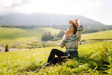 Yeşil çimen vadisinde yürüyen bir kadın büyük dağlarda. Yürüyüşçü dinleniyor. Güzel Ulusal Park. Moda, güzellik, turizm, dinlenme konsepti.