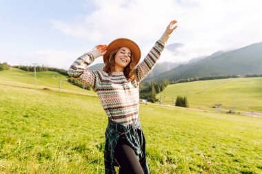 Yeşil çimen vadisinde yürüyen bir kadın büyük dağlarda. Yürüyüşçü dinleniyor. Güzel Ulusal Park. Moda, güzellik, turizm, dinlenme konsepti.