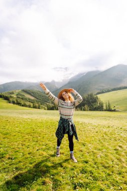 Yeşil çimen vadisinde yürüyen bir kadın büyük dağlarda. Yürüyüşçü dinleniyor. Güzel Ulusal Park. Moda, güzellik, turizm, dinlenme konsepti.