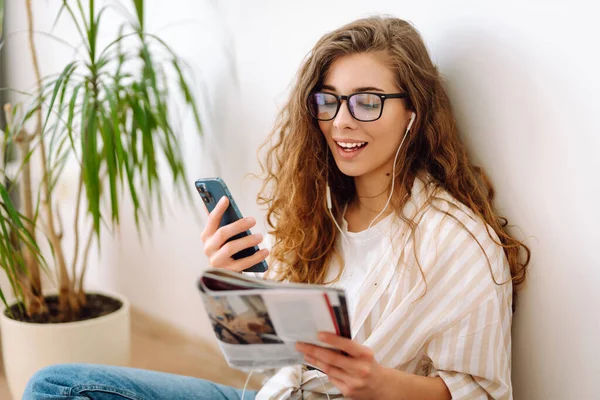 Cep telefonu modern teknolojisini kullanarak elinde akıllı telefon tutan mutlu bir kadın uzaktan çalışırken ya da öğrenirken cep telefonuna bakıyor, evde mesajlar yolluyor. İnternetten alışveriş, blog yazma, iletişim.