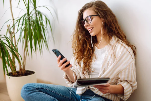 Cep telefonu modern teknolojisini kullanarak elinde akıllı telefon tutan mutlu bir kadın uzaktan çalışırken ya da öğrenirken cep telefonuna bakıyor, evde mesajlar yolluyor. İnternetten alışveriş, blog yazma, iletişim.