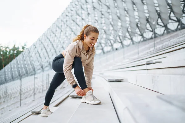 A woman does sports on the street. Fitness and a healthy lifestyle. The trainer does exercises for stretching the body. Sport, Active life, sports training, healthy lifestyle.