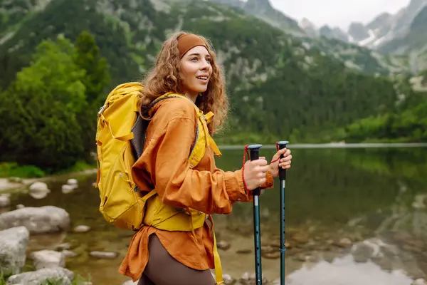 Sarı sırt çantalı mutlu kadın dağ manzarasının tadını çıkarıyor. Macera, seyahat, spor, aktif hayat.