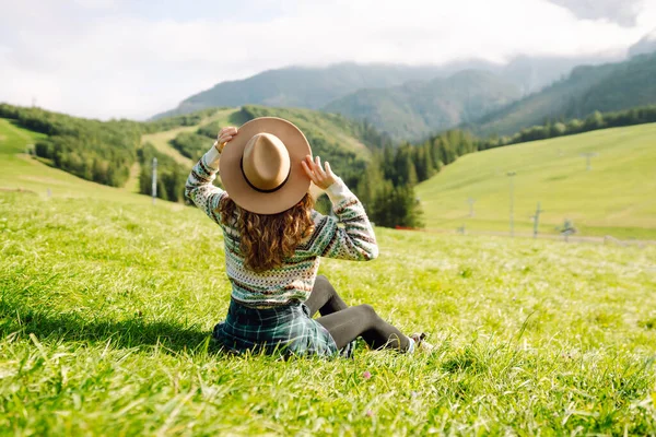 Yeşil çimen vadisinde yürüyen bir kadın büyük dağlarda. Yürüyüşçü dinleniyor. Güzel Ulusal Park. Moda, güzellik, turizm, dinlenme konsepti.