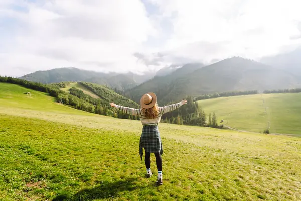 Yeşil çimen vadisinde yürüyen bir kadın büyük dağlarda. Yürüyüşçü dinleniyor. Güzel Ulusal Park. Moda, güzellik, turizm, dinlenme konsepti.