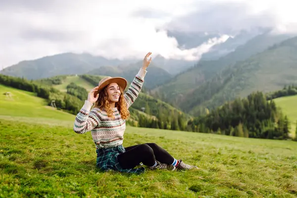 Yeşil çimen vadisinde yürüyen bir kadın büyük dağlarda. Yürüyüşçü dinleniyor. Güzel Ulusal Park. Moda, güzellik, turizm, dinlenme konsepti.