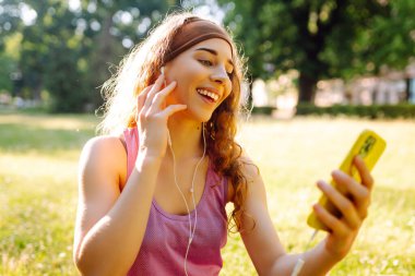 Genç bir kadın telefon ekranına el sallıyor, fitness eğitmeniyle online konferans yapıyor, video blogu kaydediyor. Güzel bir kadın eğitmen ya da takipçi. Spor, aktif yaşam, sağlıklı yaşam tarzı.