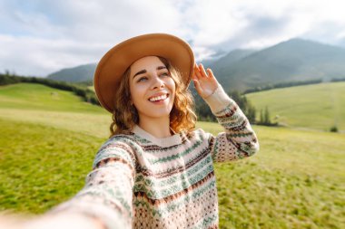 Doğada selfie çeken güzel bir genç kadın. Yaşam tarzı, seyahat, turizm, doğa, aktif yaşam.