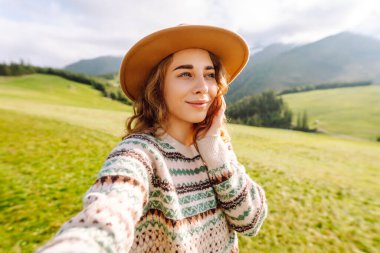 Doğada selfie çeken güzel bir genç kadın. Yaşam tarzı, seyahat, turizm, doğa, aktif yaşam.