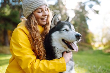 Sarı paltolu güzel genç bir kadın evcil köpeğiyle parkta yürüyor. Bir evcil hayvan sahibi köpeğiyle vakit geçirir. Eğlence anlayışı, eğlence.