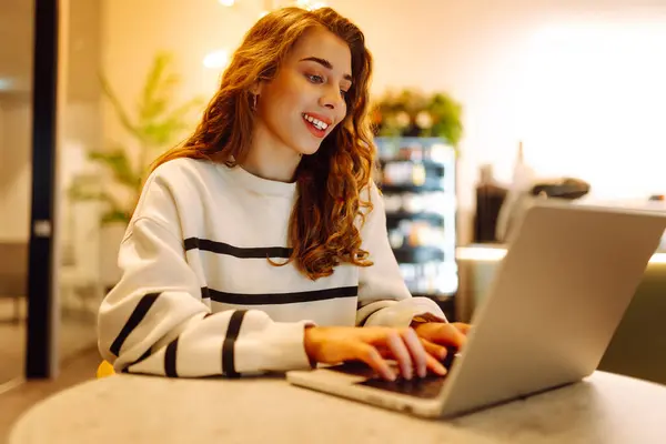 Young woman sitting on cafe with laptop. Beautiful college student on a cafe. Concept for education, business, blog or freelance.