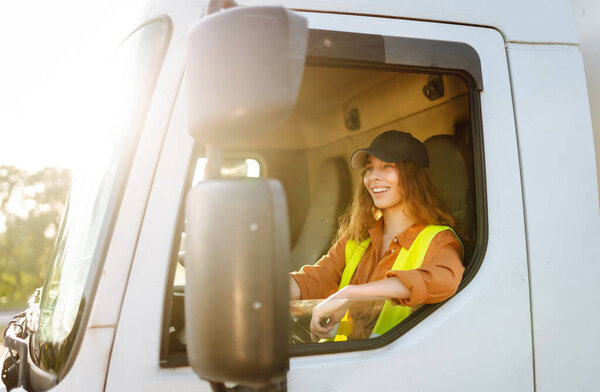 Female driver looking out of truck window. Transport industry theme