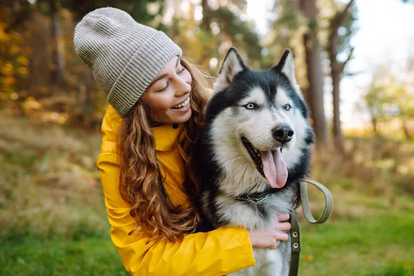 Sarı paltolu güzel genç bir kadın evcil köpeğiyle parkta yürüyor. Bir evcil hayvan sahibi köpeğiyle vakit geçirir. Eğlence anlayışı, eğlence.