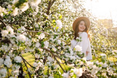 Çiçek açan bahar bahçesinde kokunun tadını çıkaran genç bir kadın. Gençlik, aşk, moda, turizm ve yaşam tarzı kavramı