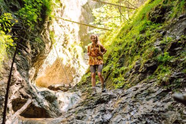 Bir mağara turistinde gezgin kadın turist macerası. Sırt çantalı genç bir kadın dışarı çıkıyor. Yürüyüş, aktif yaşam tarzı.