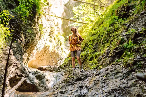 Bir mağara turistinde gezgin kadın turist macerası. Sırt çantalı genç bir kadın dışarı çıkıyor. Yürüyüş, aktif yaşam tarzı.