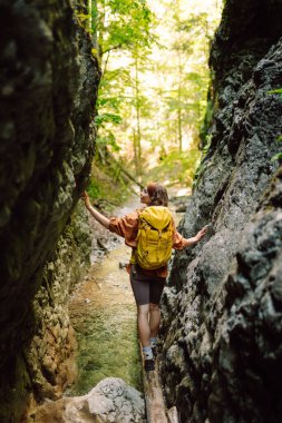 Bir mağara turistinde gezgin kadın turist macerası. Sırt çantalı genç bir kadın dışarı çıkıyor. Yürüyüş, aktif yaşam tarzı.