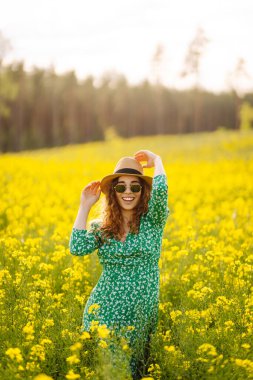 Güneşli yaz gününde çiçek açan tarlada yürüyen güzel bir kadın. Doğa, tatil, rahatlama ve yaşam tarzı. Yaz manzarası.