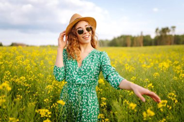 Güneşli yaz gününde çiçek açan tarlada yürüyen güzel bir kadın. Doğa, tatil, rahatlama ve yaşam tarzı. Yaz manzarası.