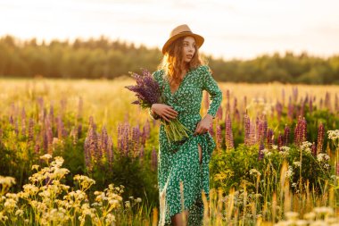 Güzel bir kadın çiçek kokulu lavanta tarlalarında duruyor. Doğa, tatil, rahatlama ve yaşam tarzı. Şifalı bitkilerin toplanması
