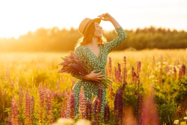 Güzel bir kadın çiçek kokulu lavanta tarlalarında duruyor. Doğa, tatil, rahatlama ve yaşam tarzı. Şifalı bitkilerin toplanması