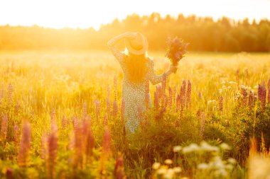 Güzel bir kadın çiçek kokulu lavanta tarlalarında duruyor. Doğa, tatil, rahatlama ve yaşam tarzı. Şifalı bitkilerin toplanması